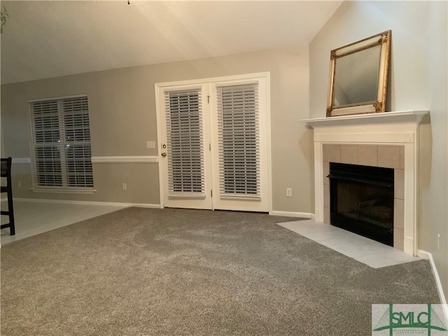 unfurnished living room featuring lofted ceiling, a tile fireplace, and carpet