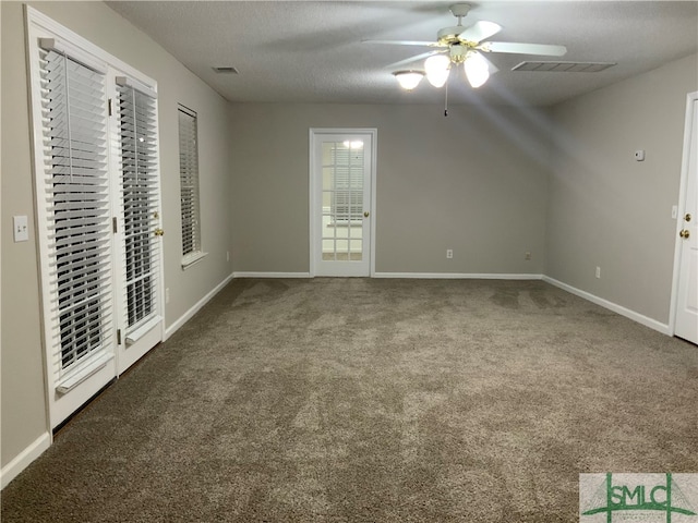 spare room with a textured ceiling, dark colored carpet, and ceiling fan