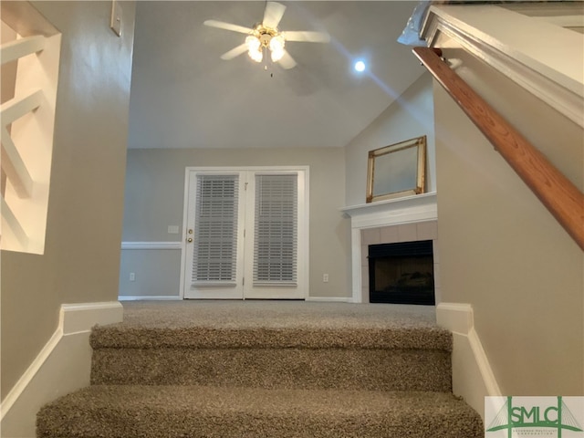 stairs featuring carpet, vaulted ceiling, ceiling fan, and a fireplace