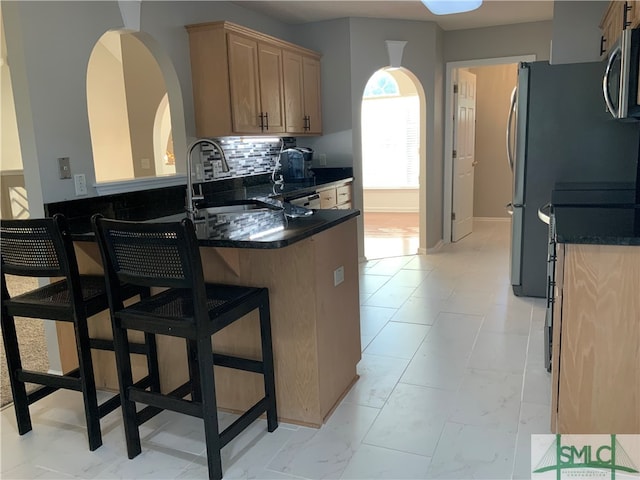 kitchen featuring a kitchen breakfast bar, light tile flooring, kitchen peninsula, backsplash, and sink