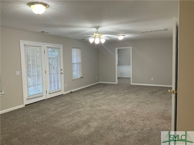 unfurnished room with ceiling fan, dark carpet, and a textured ceiling