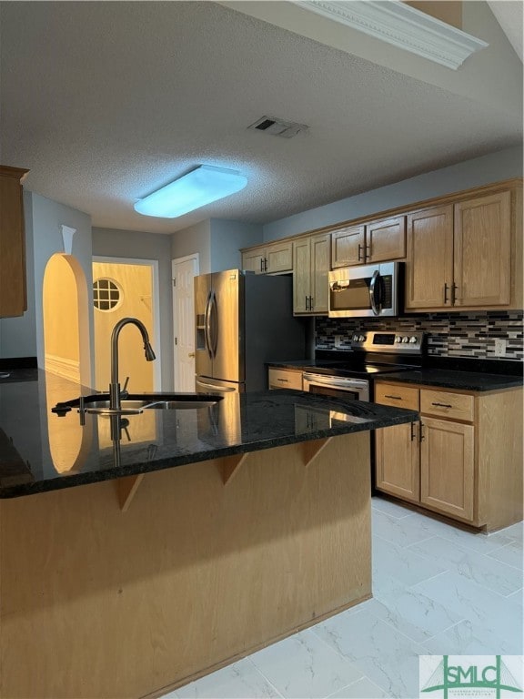 kitchen with backsplash, appliances with stainless steel finishes, light tile floors, and dark stone counters