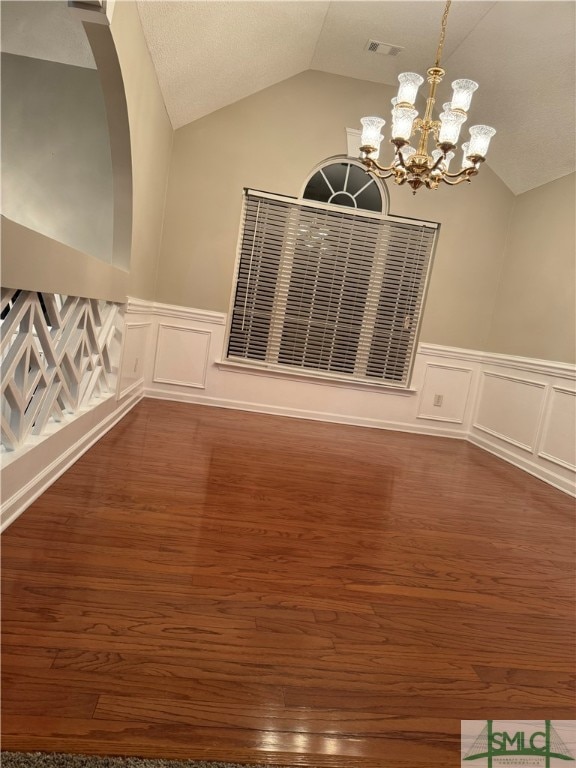 spare room with vaulted ceiling, dark wood-type flooring, and a chandelier