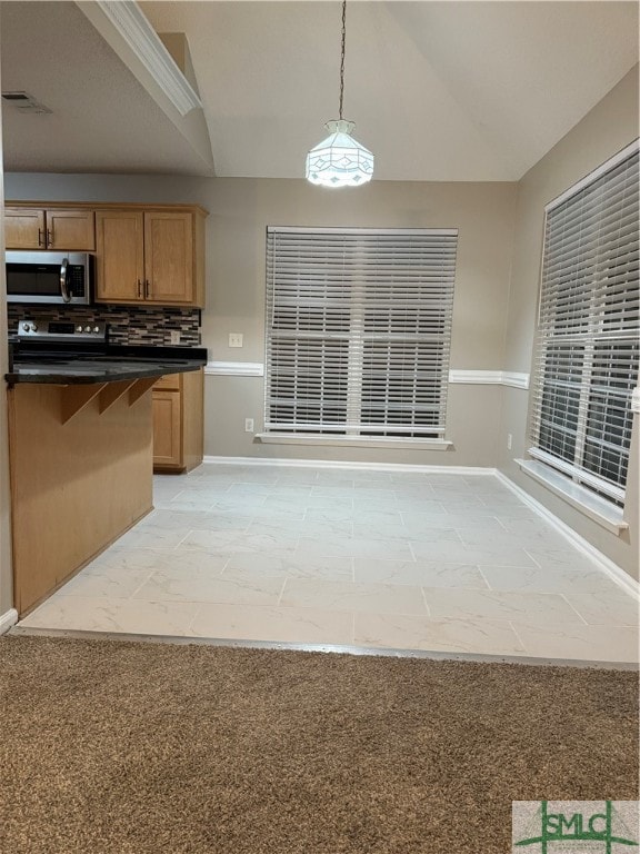 kitchen with decorative light fixtures, stainless steel appliances, light tile floors, vaulted ceiling, and tasteful backsplash