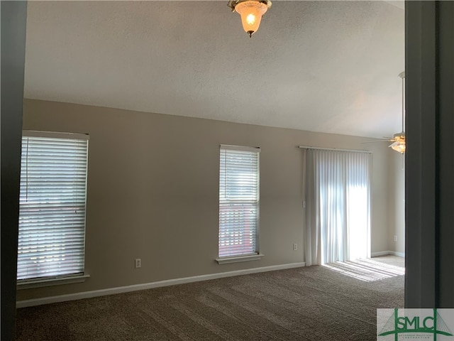 empty room featuring dark carpet, ceiling fan, and a textured ceiling