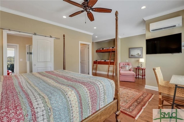 bedroom featuring ornamental molding, a barn door, hardwood / wood-style flooring, an AC wall unit, and ceiling fan