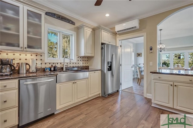 kitchen featuring a wall mounted air conditioner, light hardwood / wood-style flooring, backsplash, cream cabinets, and stainless steel appliances