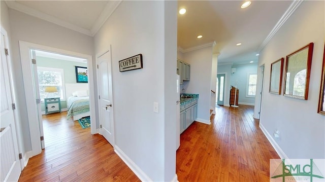 corridor featuring crown molding, hardwood / wood-style flooring, and a wealth of natural light