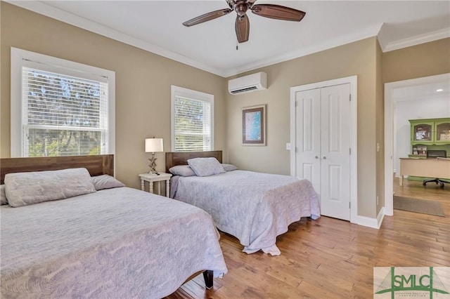 bedroom with a wall mounted air conditioner, light hardwood / wood-style floors, ceiling fan, and multiple windows