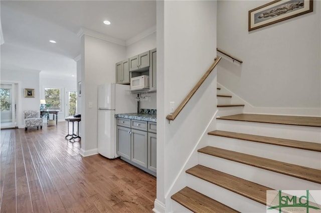 stairs with ornamental molding and wood-type flooring