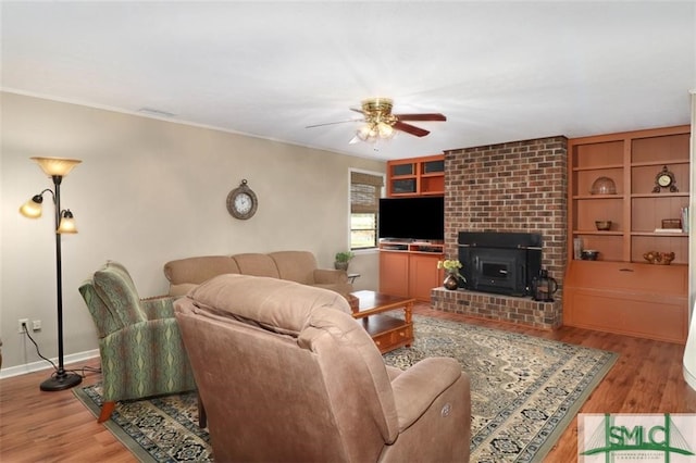 living room with hardwood / wood-style flooring, a wood stove, and ceiling fan