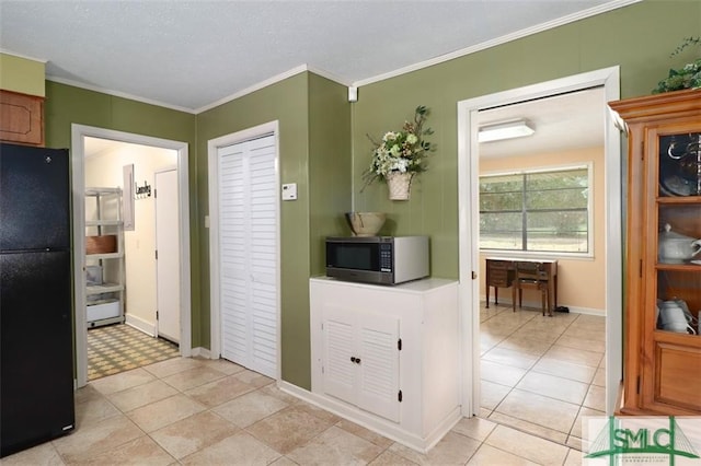 kitchen with light tile patterned floors, black fridge, and crown molding