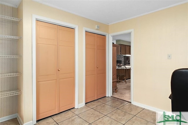 interior space featuring light tile patterned floors, two closets, and crown molding