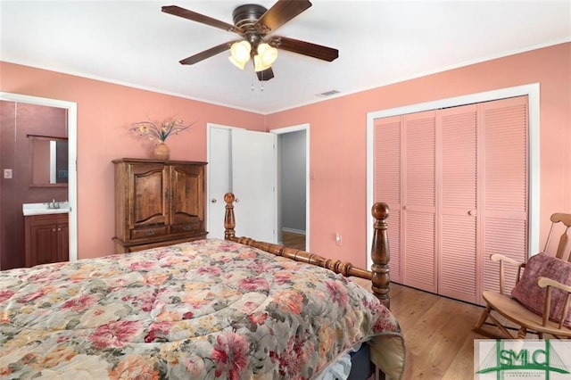 bedroom with ensuite bathroom, sink, light hardwood / wood-style flooring, ceiling fan, and a closet