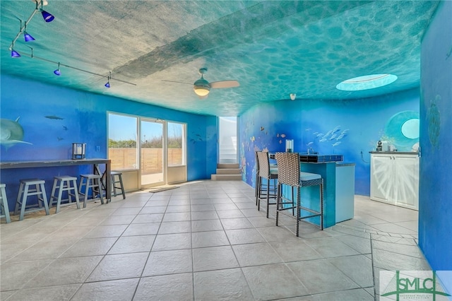 kitchen with ceiling fan, light tile flooring, a kitchen breakfast bar, and kitchen peninsula