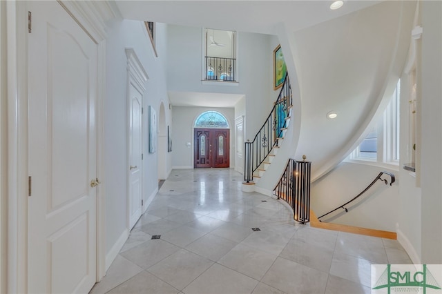 entrance foyer with a healthy amount of sunlight, a high ceiling, and light tile flooring