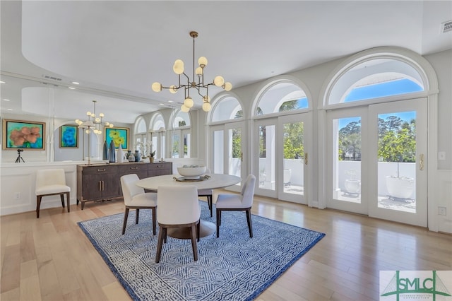 dining space with an inviting chandelier, light hardwood / wood-style floors, and a wealth of natural light