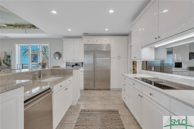 kitchen featuring sink, stainless steel appliances, light stone counters, and white cabinets