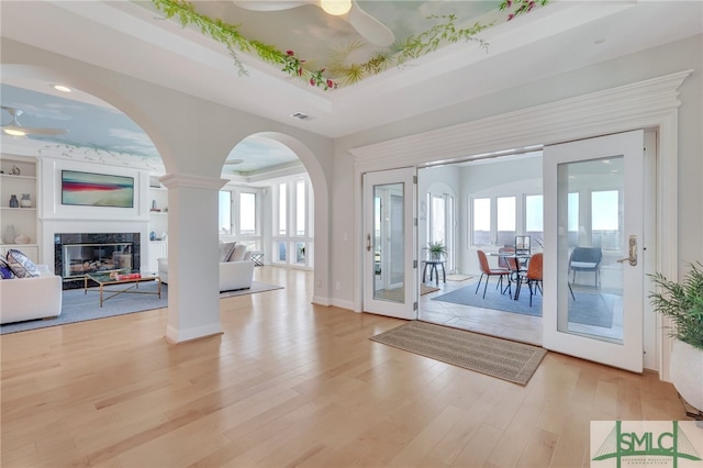 entryway with built in features, ceiling fan, light hardwood / wood-style flooring, and a raised ceiling