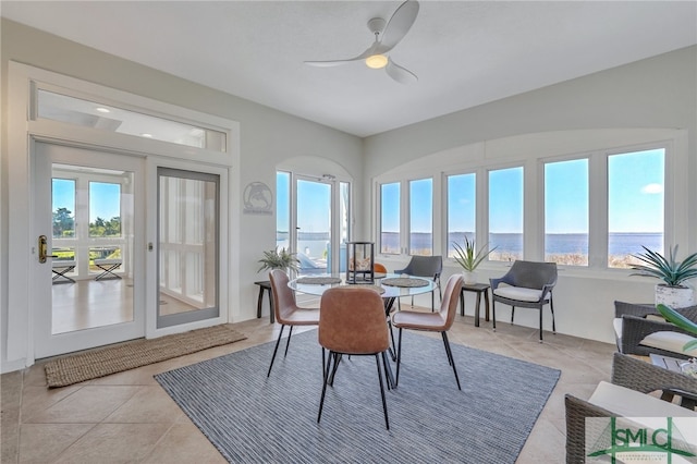 dining space featuring light tile floors, french doors, ceiling fan, and a water view