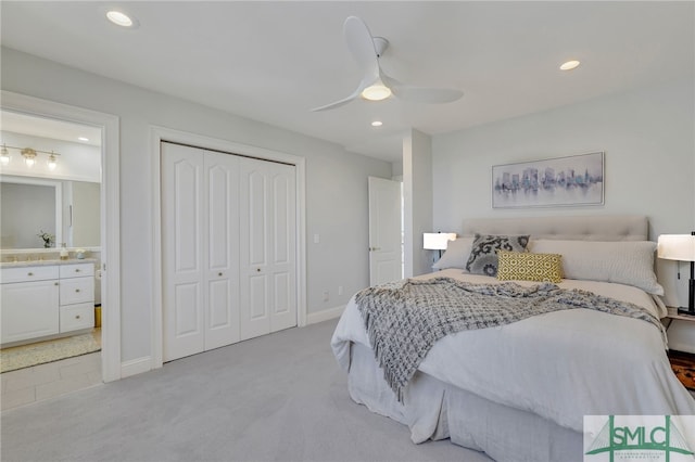 carpeted bedroom with connected bathroom, a closet, ceiling fan, and sink