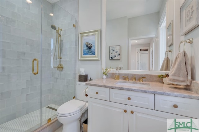 bathroom with a shower with shower door, toilet, and vanity with extensive cabinet space