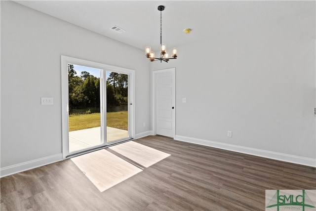 spare room with an inviting chandelier and dark hardwood / wood-style floors