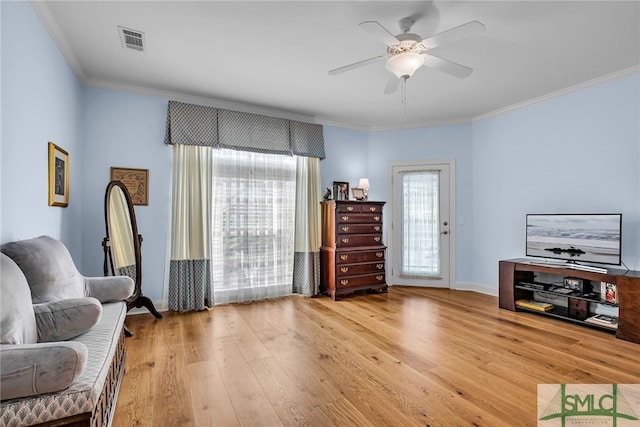 sitting room with ceiling fan, crown molding, and light wood-type flooring