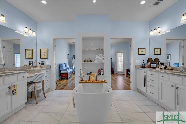 bathroom with tile flooring, a washtub, and double vanity