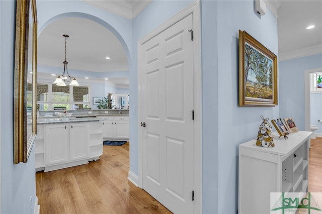 hall featuring a notable chandelier, light hardwood / wood-style flooring, and ornamental molding