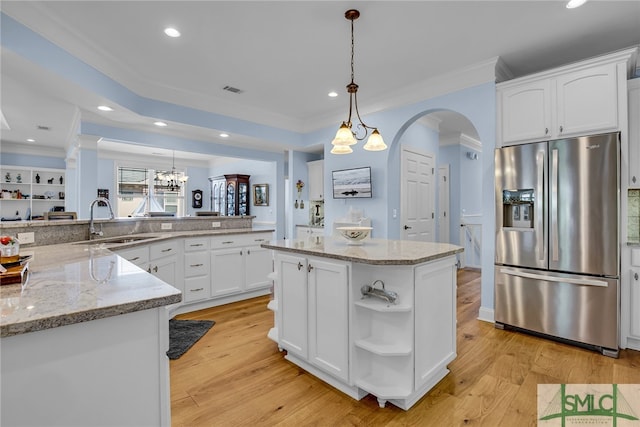 kitchen featuring decorative light fixtures, light wood-type flooring, kitchen peninsula, and stainless steel fridge