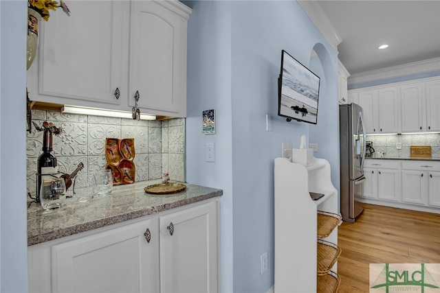 kitchen featuring white cabinetry, stainless steel refrigerator with ice dispenser, and tasteful backsplash