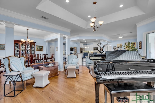 interior space featuring light wood-type flooring, a notable chandelier, crown molding, and a tray ceiling