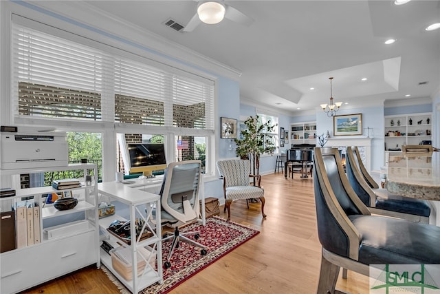 office space with light hardwood / wood-style floors, a wealth of natural light, a raised ceiling, and ceiling fan with notable chandelier