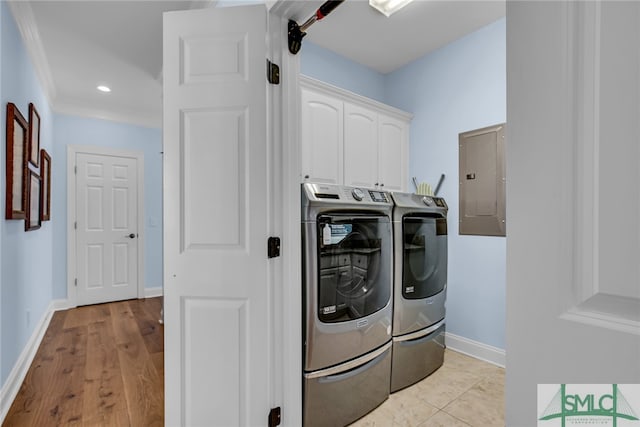 clothes washing area with crown molding, cabinets, light wood-type flooring, and washing machine and dryer