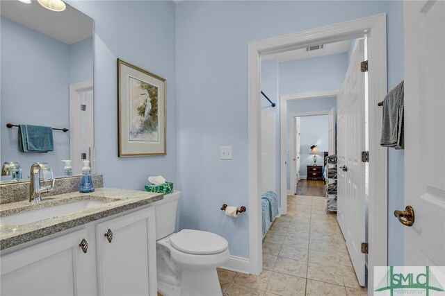 bathroom featuring tile flooring, toilet, and vanity with extensive cabinet space