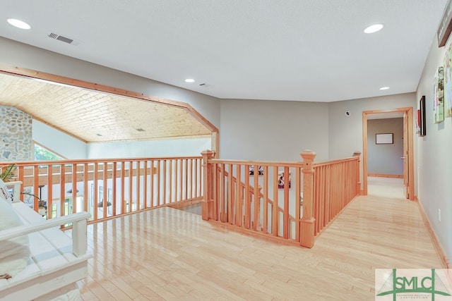 corridor with light hardwood / wood-style floors and vaulted ceiling