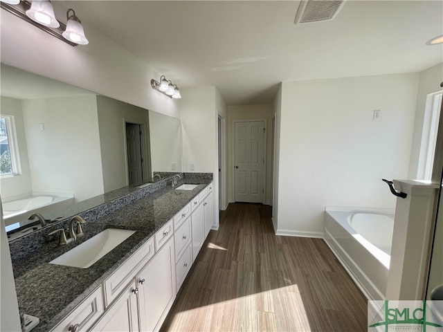 bathroom featuring vanity, wood-type flooring, and a washtub