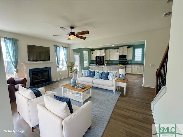 living room featuring wood-type flooring, ceiling fan, and sink