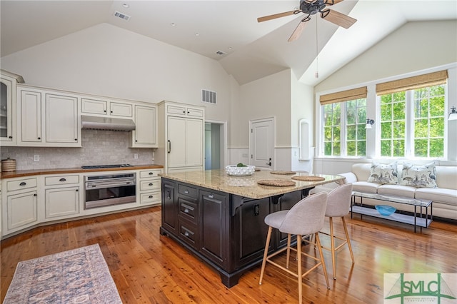 kitchen with backsplash, appliances with stainless steel finishes, light hardwood / wood-style floors, and ceiling fan