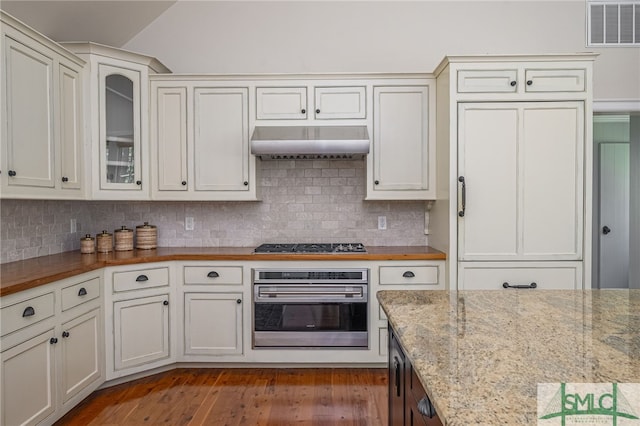 kitchen featuring wall chimney exhaust hood, wood counters, dark wood-type flooring, stainless steel appliances, and tasteful backsplash