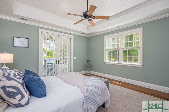 bedroom featuring a tray ceiling, wood-type flooring, ceiling fan, and multiple windows