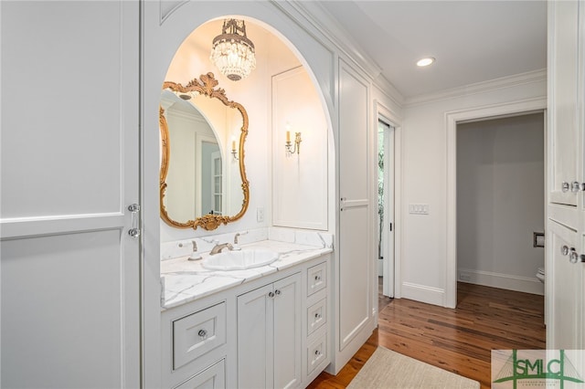 bathroom featuring crown molding, vanity, a chandelier, hardwood / wood-style flooring, and toilet