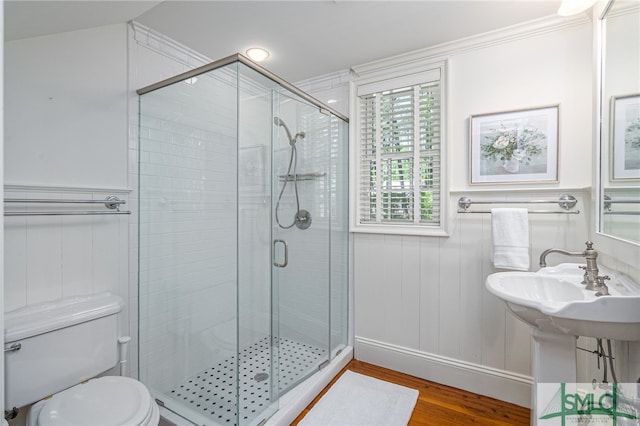 bathroom featuring a shower with shower door, toilet, hardwood / wood-style flooring, and crown molding