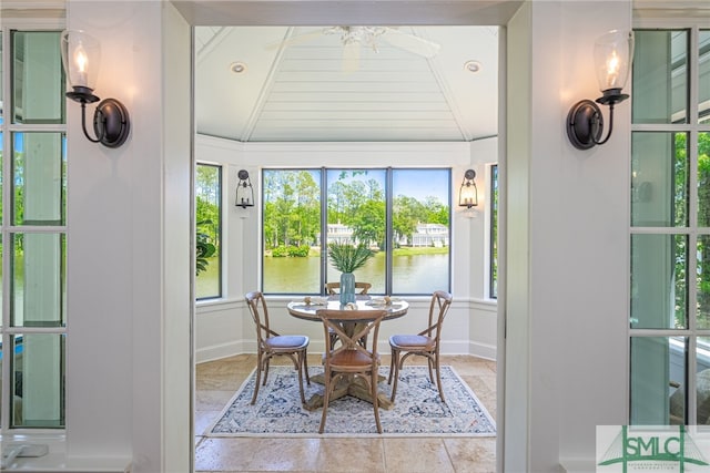 tiled dining area with lofted ceiling and a water view