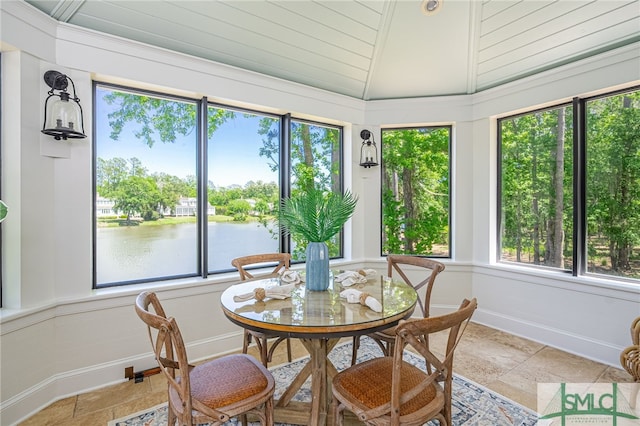 sunroom / solarium with lofted ceiling, a water view, and a wealth of natural light