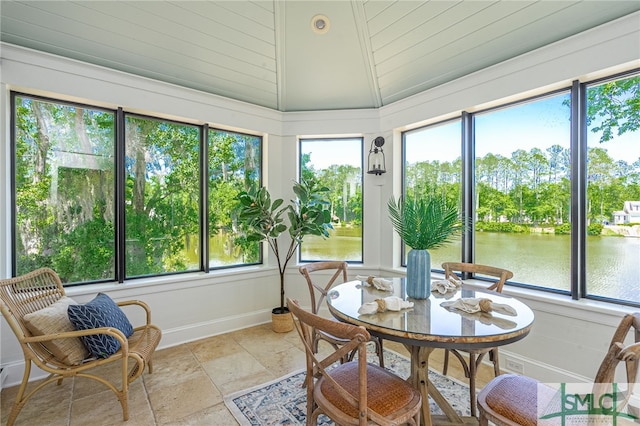 sunroom with a healthy amount of sunlight, lofted ceiling, and a water view