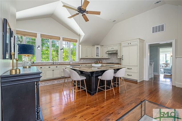 kitchen featuring white cabinets, light stone countertops, a kitchen island, and dark wood-type flooring