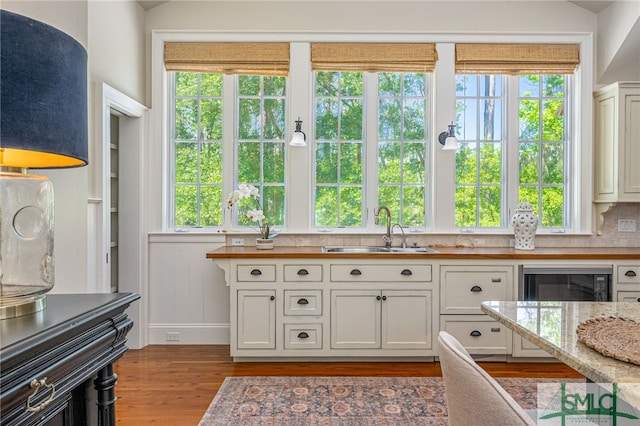 kitchen featuring sink, a healthy amount of sunlight, light wood-type flooring, and white cabinetry