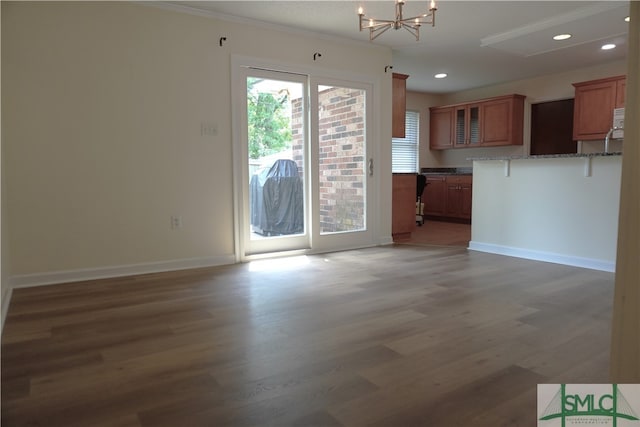 unfurnished living room with ornamental molding, dark hardwood / wood-style flooring, and an inviting chandelier